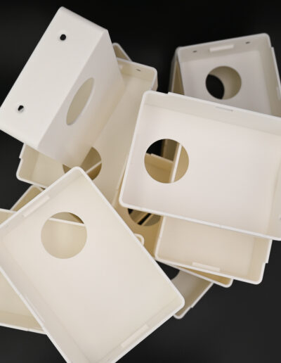 Assorted off-white custom 3D-printed electronic housing boxes with a sleek surface finish, featuring robust frames and precision-fit snap-on covers, designed for wall-mounted electronics integration.